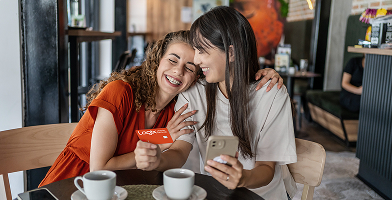 Two friends hugging while one holds a Logix Mastercard
